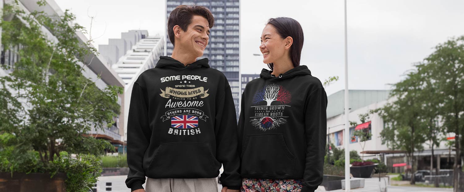 A man and a woman in black hoodies showing their national flags with an entertaining slogan on them